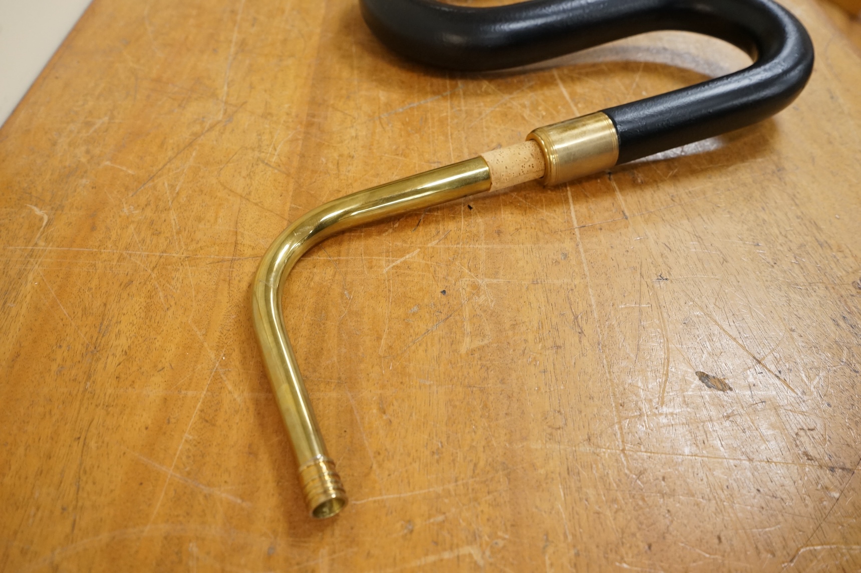 A black painted serpent open hole wind musical instrument, with brass neck (missing mouthpiece).